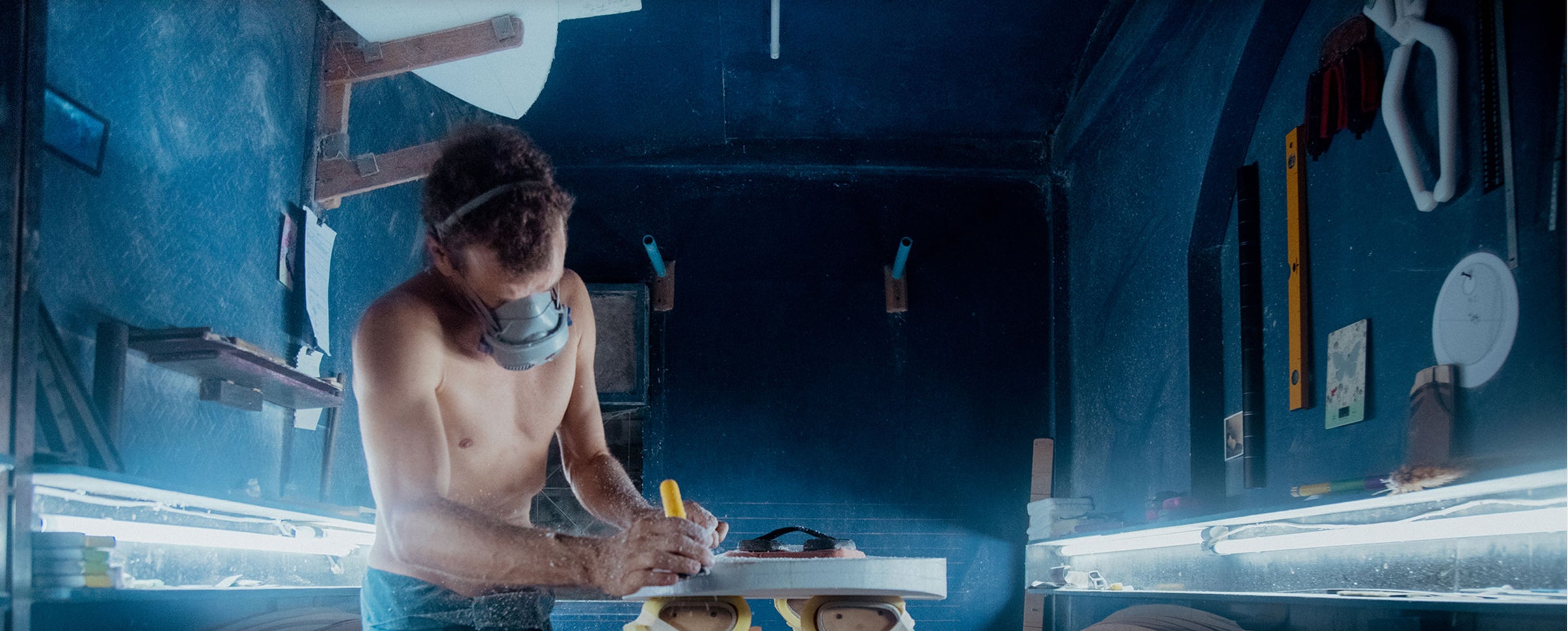 david sautebin working in workshop, sanding a board on a table.