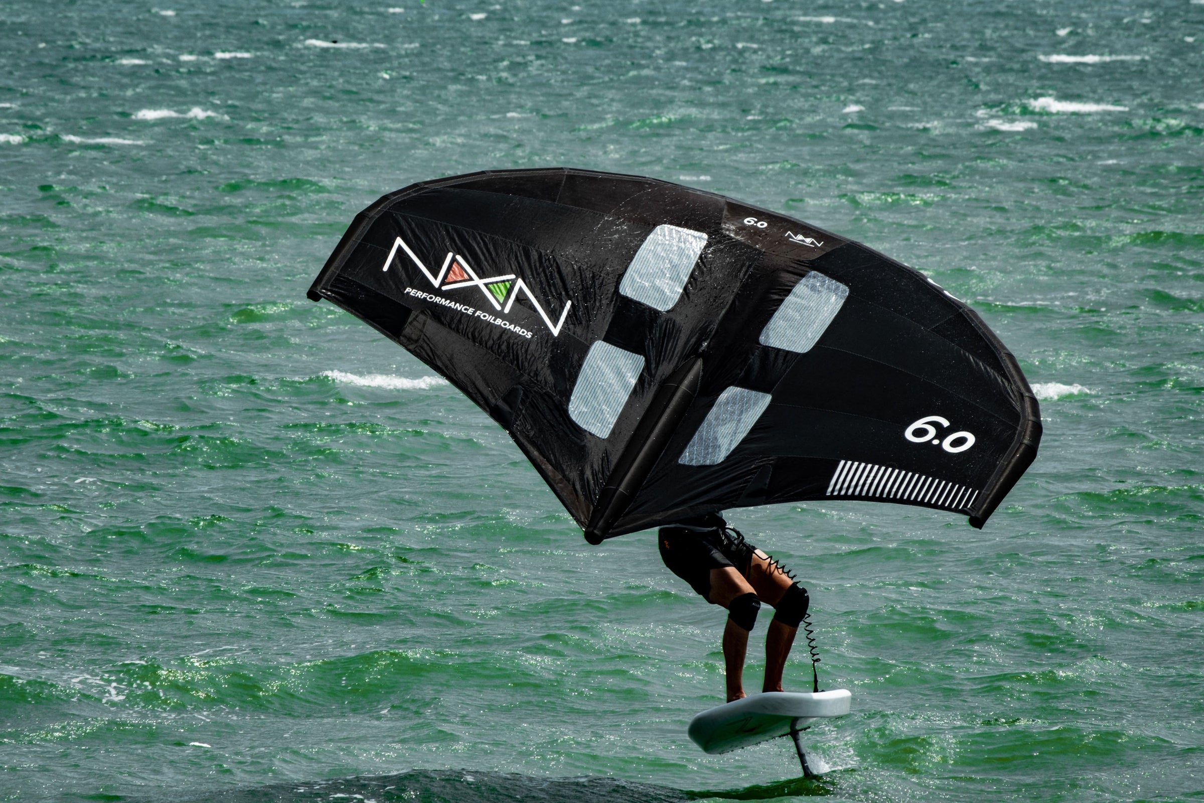 rider with a nexen wing and foil board riding towards the camera on choppy waters