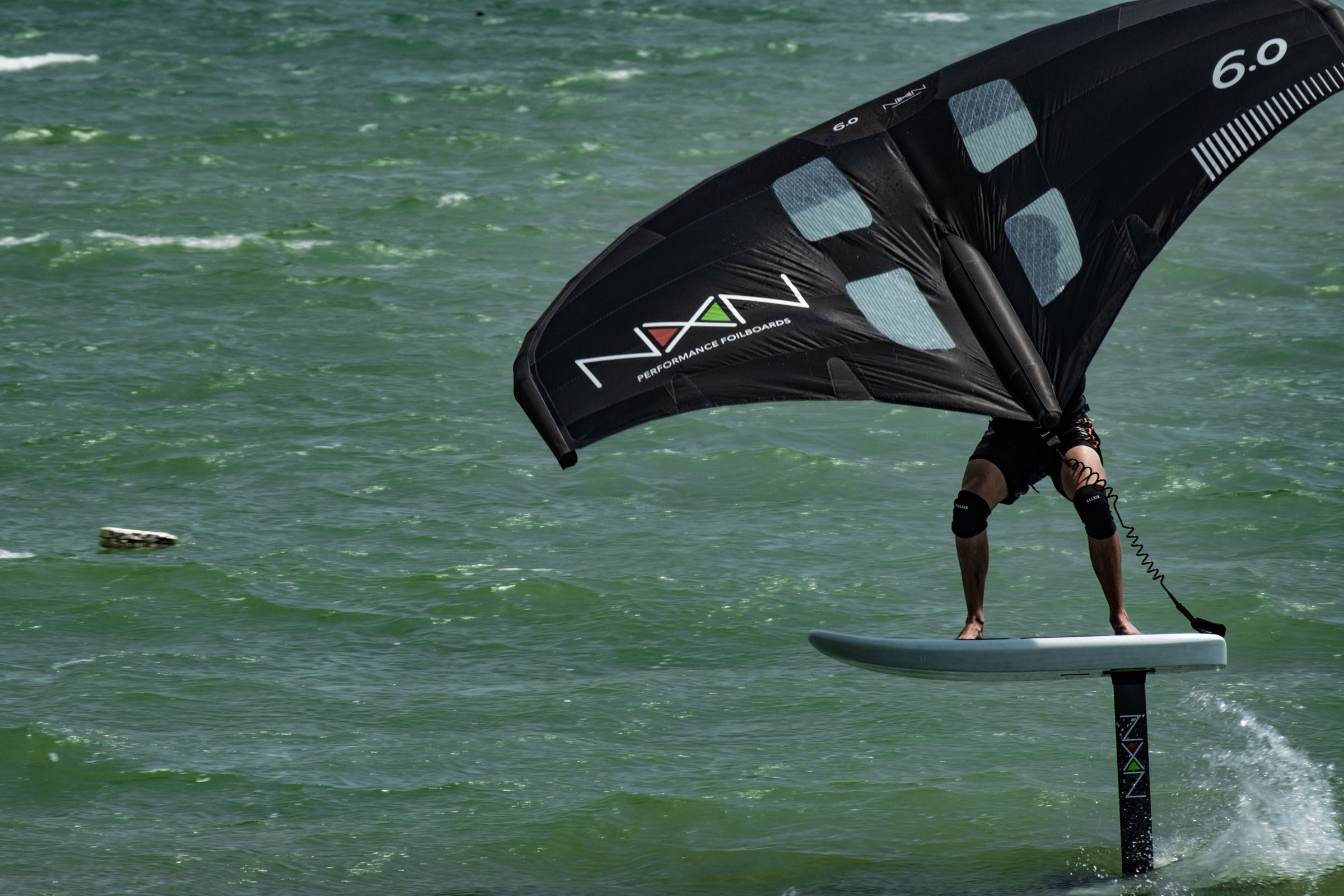 rider on nexen foil board and wing sailing through the water